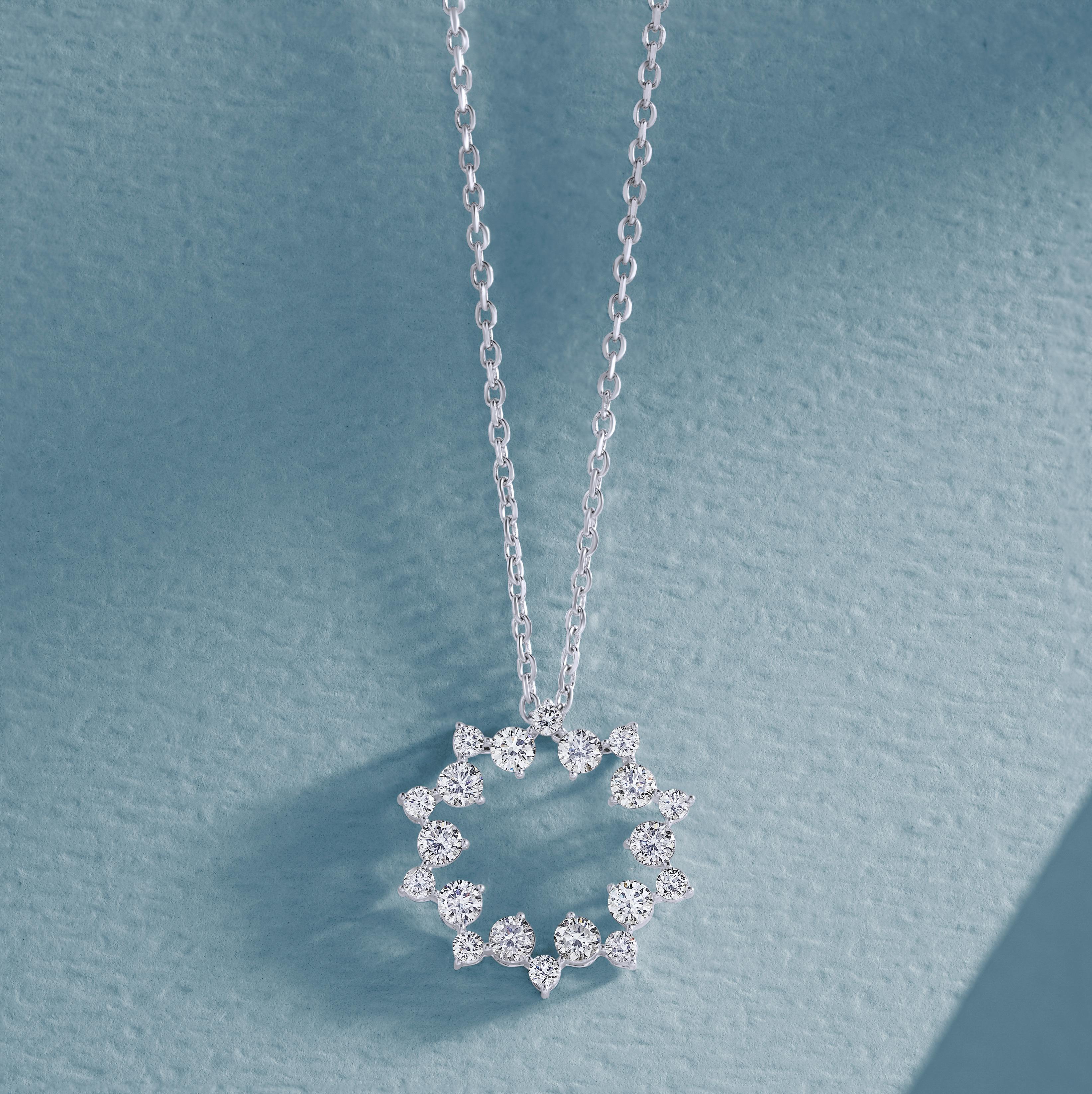 Close-up of a diamond pendant necklace on a textured blue background.