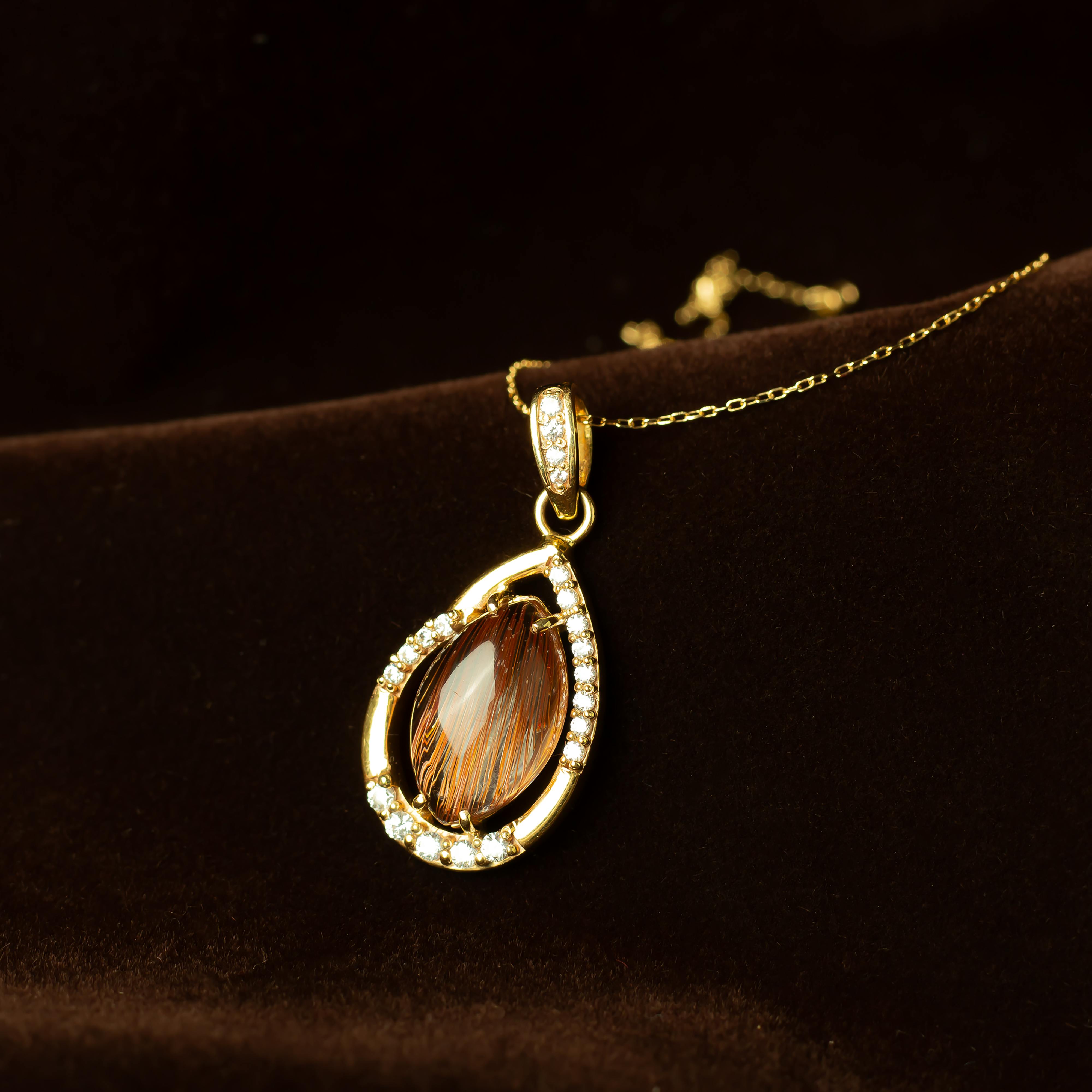 Luxurious gold teardrop necklace with diamond accents on a plush background, perfect for fashion and luxury themes.
